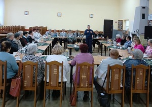 policjantka podczas prelekcji wokół stoły przy których siedzą seniorzy