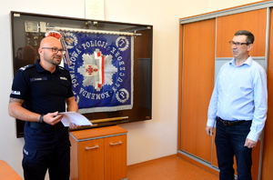 zastępca komendanta w obecności policjanta odchodzącego na emeryturę, w tle sztandar kluczborskiej jednostki