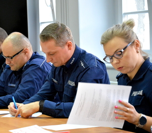 trzech funkcjonariuszy policji siedzących przy stole w trakcie rozwiazywania testu