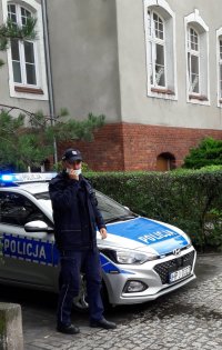 policjant stojący przy radiowozie w rejonie szkoły