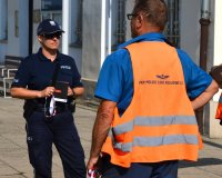 policjantka w mundurze stojąca z mężczyzną ubranym w kamizelkę z napisem Polskie Koleje Państwowe