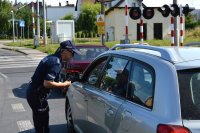 policjantka rozmawiająca z kierowcą samochodu, wręczająca ulotki informacyjne