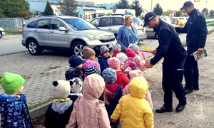 policjanci rozdający opaski odblaskowe i książeczki