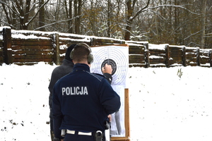 przed tarczą stoi dwóch policjantów sprawdzając przestrzeliny