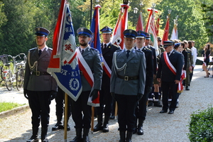 trzech policjantów umundurowanych stojących ze sztandarem