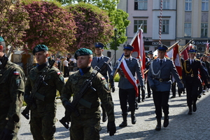 poczty sztandarowe idące wzdłuż rynku w Kluczborku pierwszy poczet policjantów
