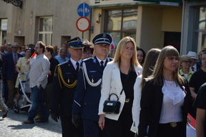 umundurowany policjant w obecności innych przedstawicieli służb mundurowych trzymający flagę Polski