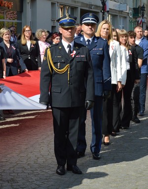 osoby stojące przy fladze Polski wśród nich umundurowany policjant