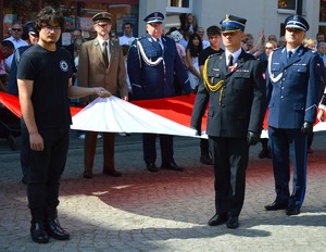 policjanci stojący trzymają flagę Polski