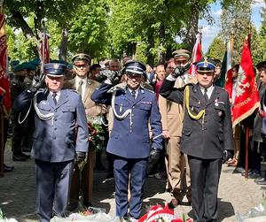 Komendant w obecności innych przedstawicieli służb mundurowych salutuje przed pomnikiem żołnierza Polskiego.