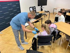 policyjny technik pokazuje materiał do zbierania odcisków palców
