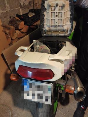 tył motocykla z otwartym siedzeniem, w schowku pod siedzeniem metalowe pudełko z białym proszkiem