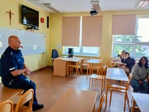 policjant siedzący na ławce prowadzący pogadankę