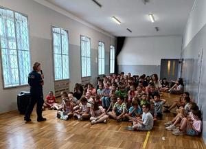 policjantka podczas prowadzonej prelekcji w tle siedzące dzieci
