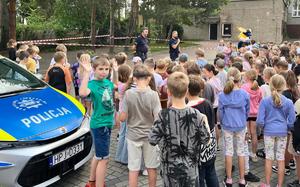 policjanci na zewnątrz prowadzą prelekcję w około stoją dzieci