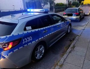 Radiowóz na sygnałach oraz zatrzymany pojazd audi i holownik