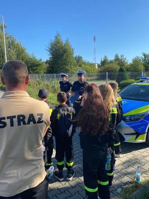 strażak z młodzieżą oraz policjanci podczas tłumaczenia zasad