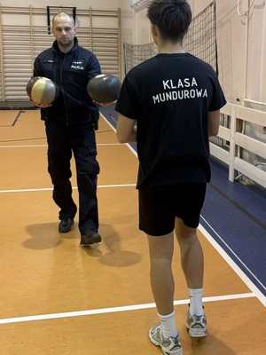 policjant z piłkami i stojący tyłem uczeń