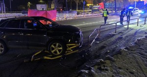 pracujący na miejscu policjanci oraz audi rozbite na barierkach