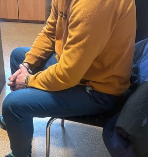 mężczyzna siedzący na krześle podczas czynności w kajdankach