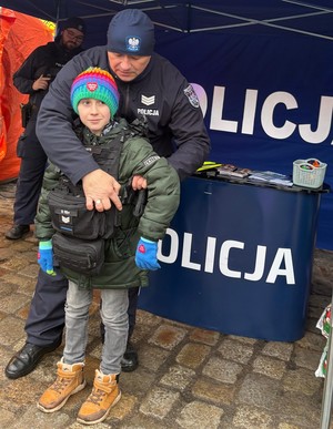 Policjant zakładający kamizelkę taktyczną chłopcu