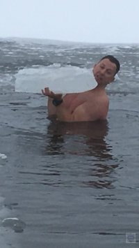 stojący w wodzie mężczyzna trzymający w rękach krę lodu