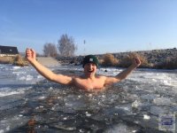 stojący w wodzie z uniesionymi rękami mężczyzna, na powierzchni wody pływające kawałki lodu.