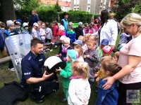 policjant prezentujący dzieciom sprzęt policyjny - kamizelka, tarcza, kask