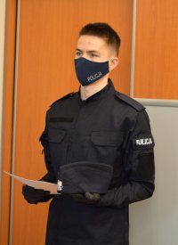 policjant w mundurze , w ręce trzymający akt slubowania